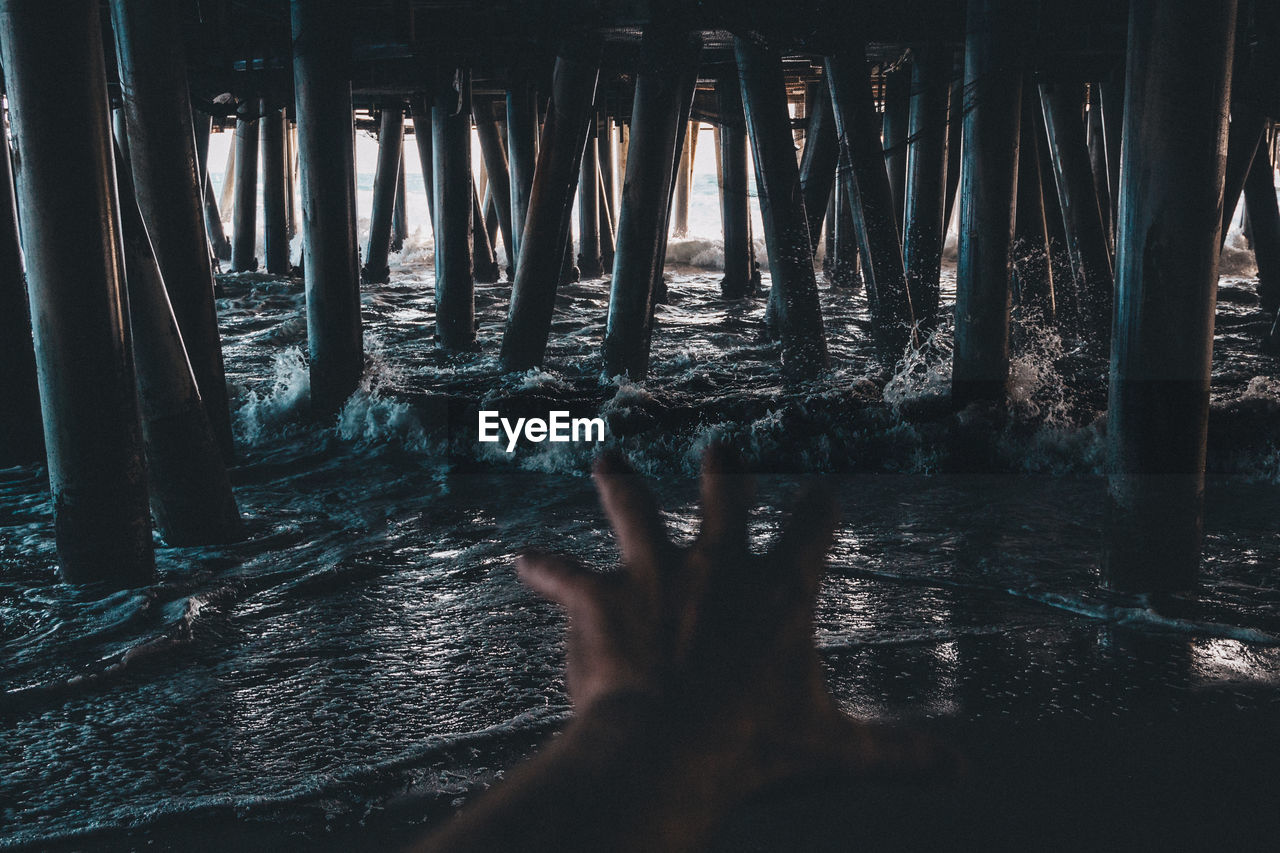 Cropped image of woman reaching pier over sea