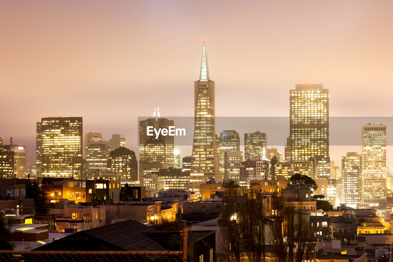 Illuminated buildings in city against sky