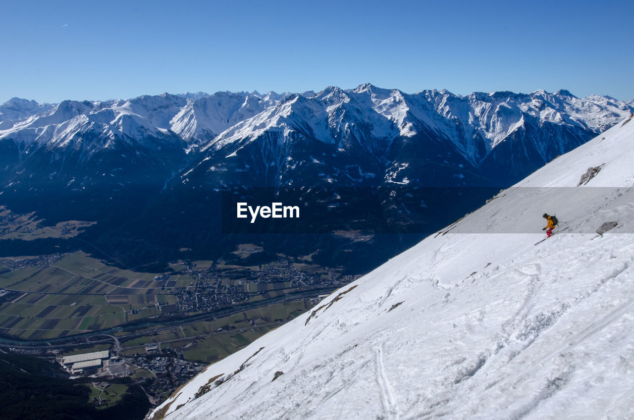 Snow covered landscape against clear blue sky