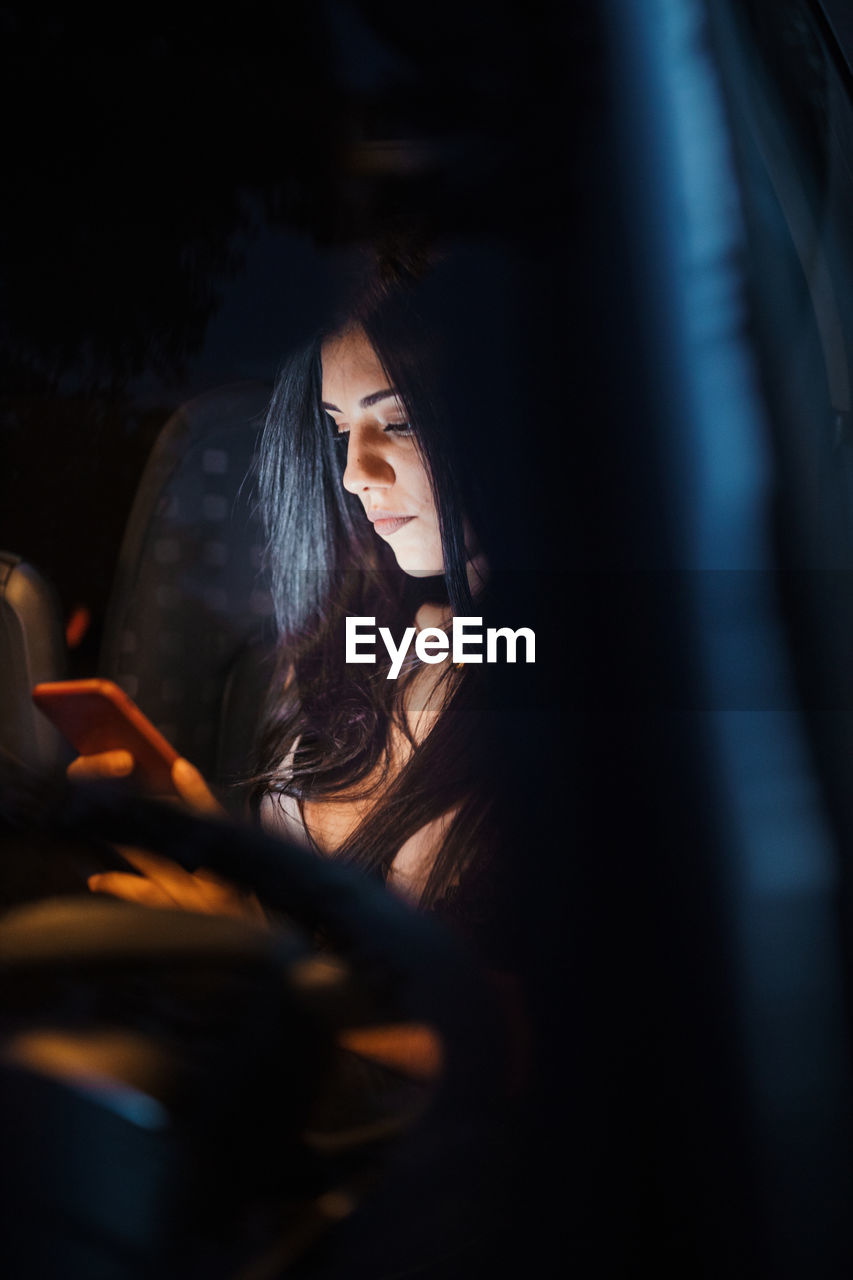 Young woman inside a car using her smartphone