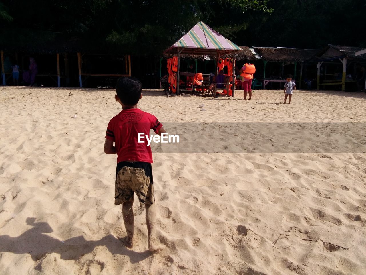 REAR VIEW OF FRIENDS PLAYING ON BEACH