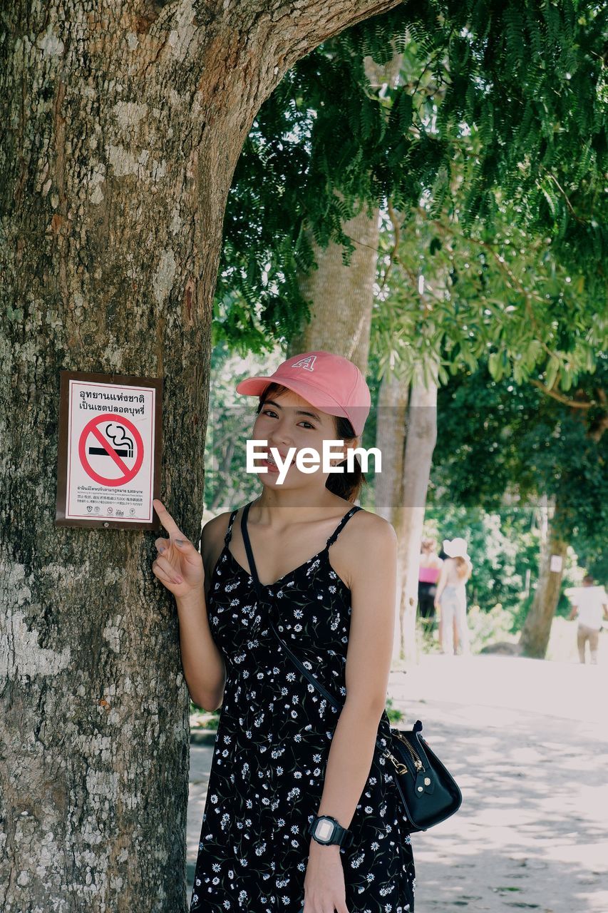 WOMAN STANDING BY TREE