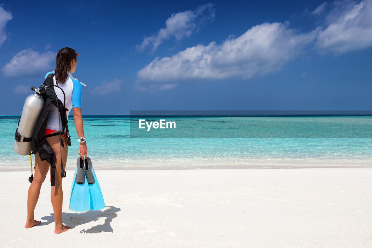 Rear view of woman with scuba diving equipment at beach