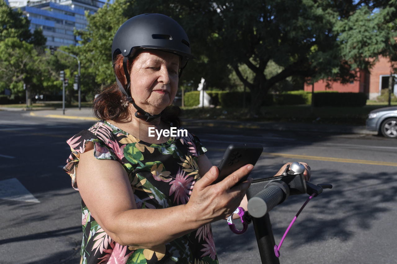 Woman with electric push scooter looking at mobile phone