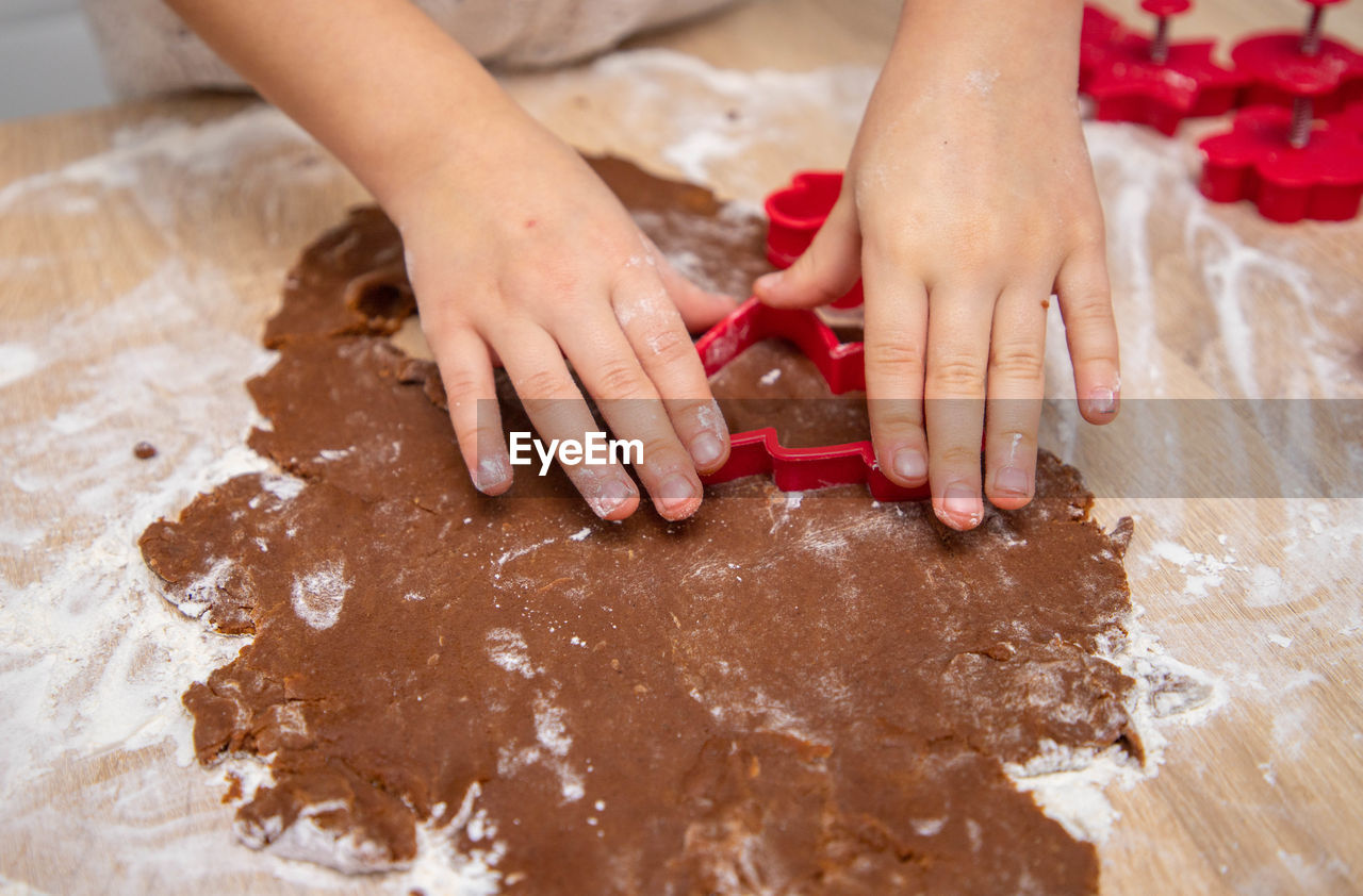 Child making christmas cookies from gingerbread dough and cookie cutters
