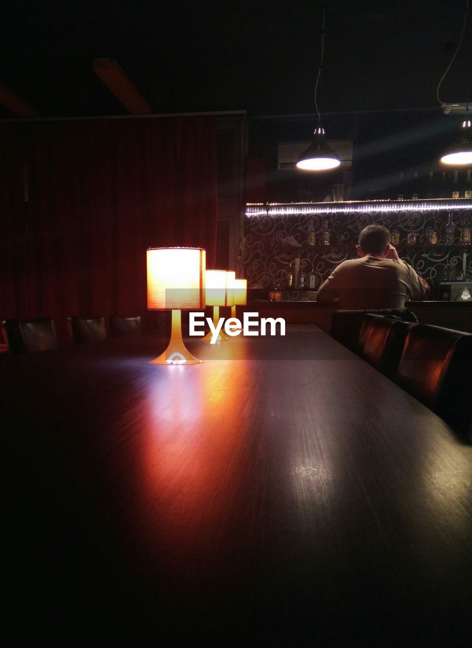 Illuminated lamp shades on table at bar