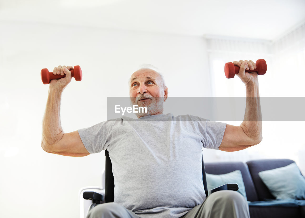 Low angle view of man lifting dumbbells at home