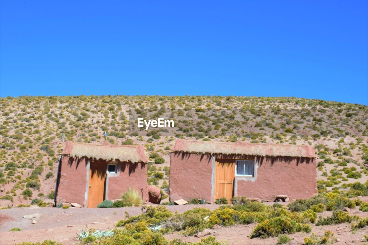 House on desert against clear blue sky