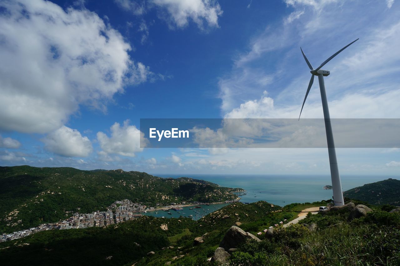 Wind turbines on mountain against sky