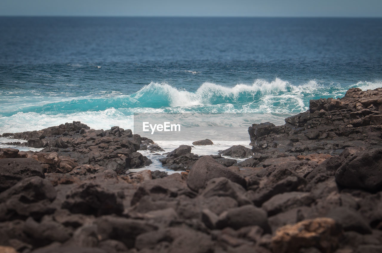 Tilt shift effect of oceanic waves against the boca de abaco volcanic rocks coast, lanzarote