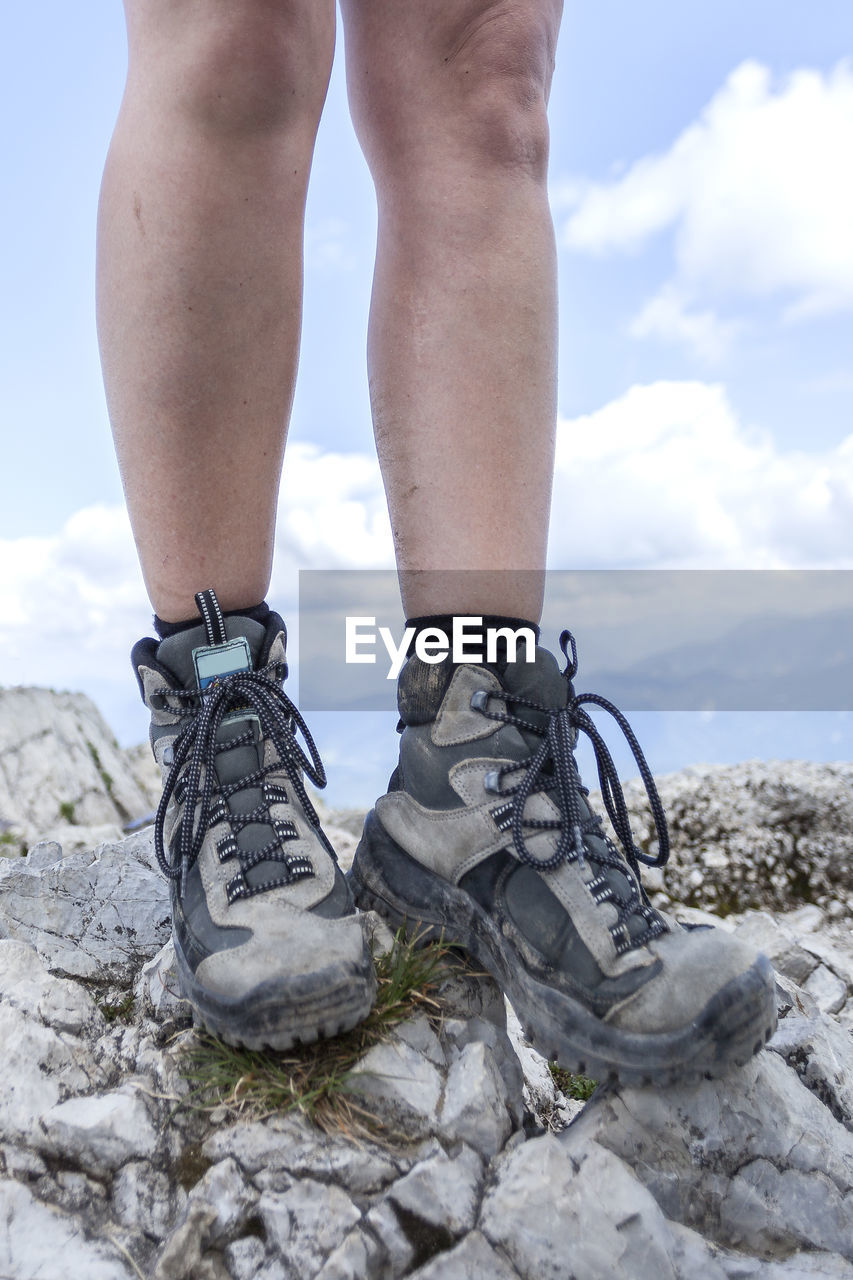 human leg, low section, footwear, one person, shoe, nature, limb, cloud, rock, sky, human limb, leisure activity, day, mountain, adult, spring, standing, hiking, adventure, outdoors, human foot, sports, walking, activity, winter, lifestyles, outdoor shoe, men, land, climbing, close-up, environment, blue