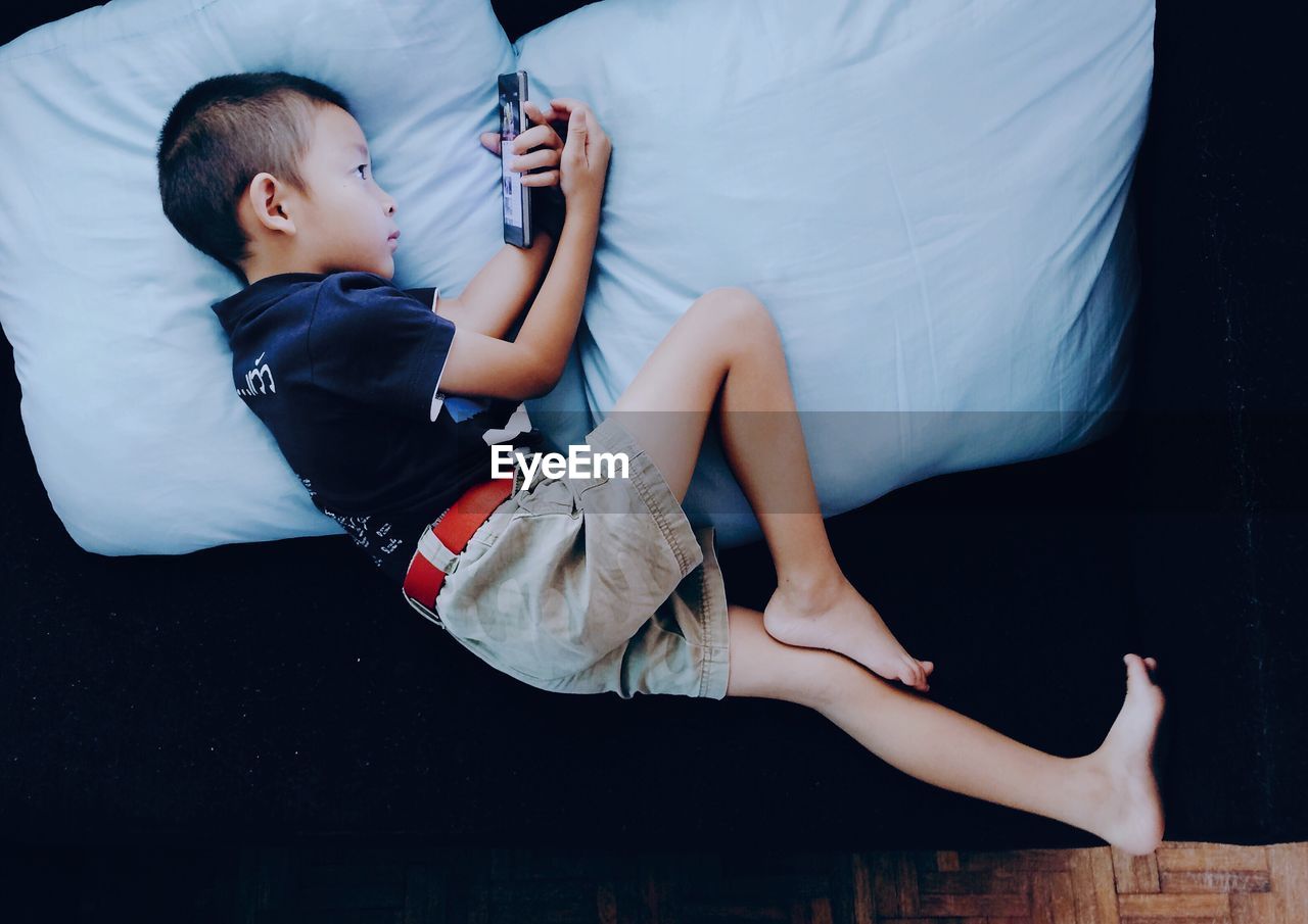 High angle view of boy using smart phone on sofa at home