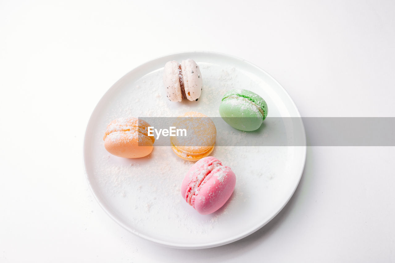 Close-up of multi colored macaroons in plate on white background