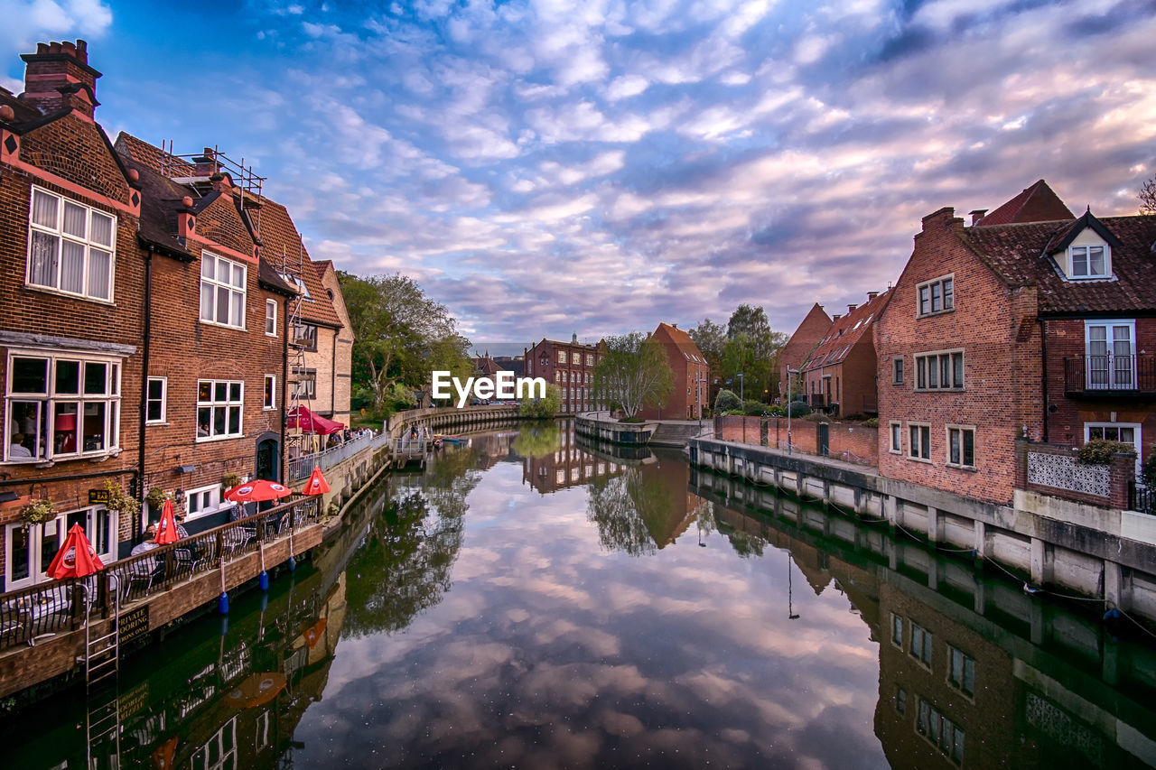 Canal amidst buildings in town against sky