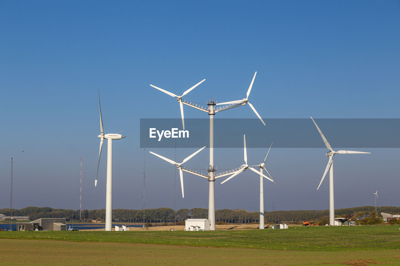 low angle view of windmills on field against clear blue sky