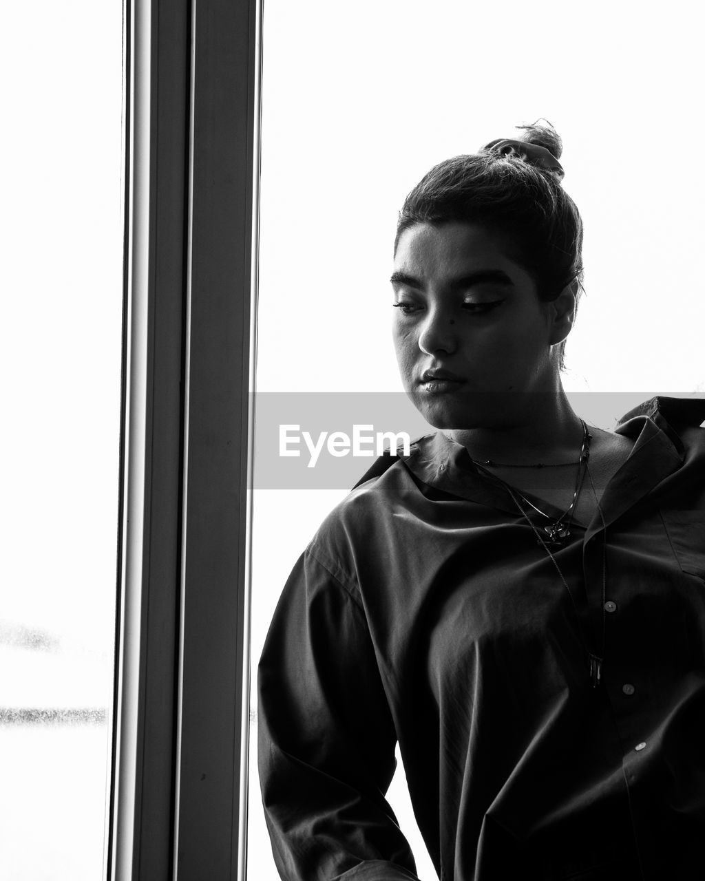 Portrait of young woman looking through window