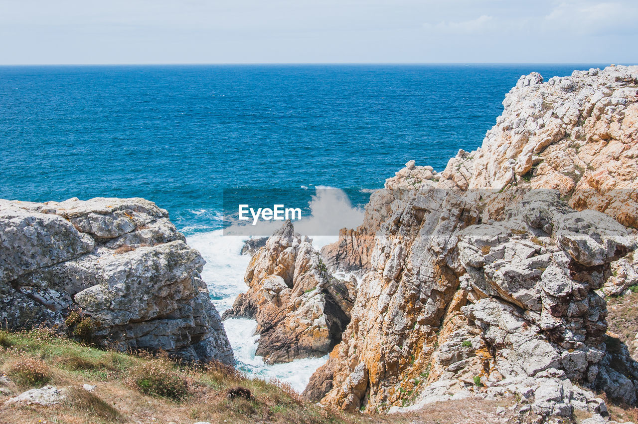 SCENIC VIEW OF ROCKY BEACH AGAINST SKY