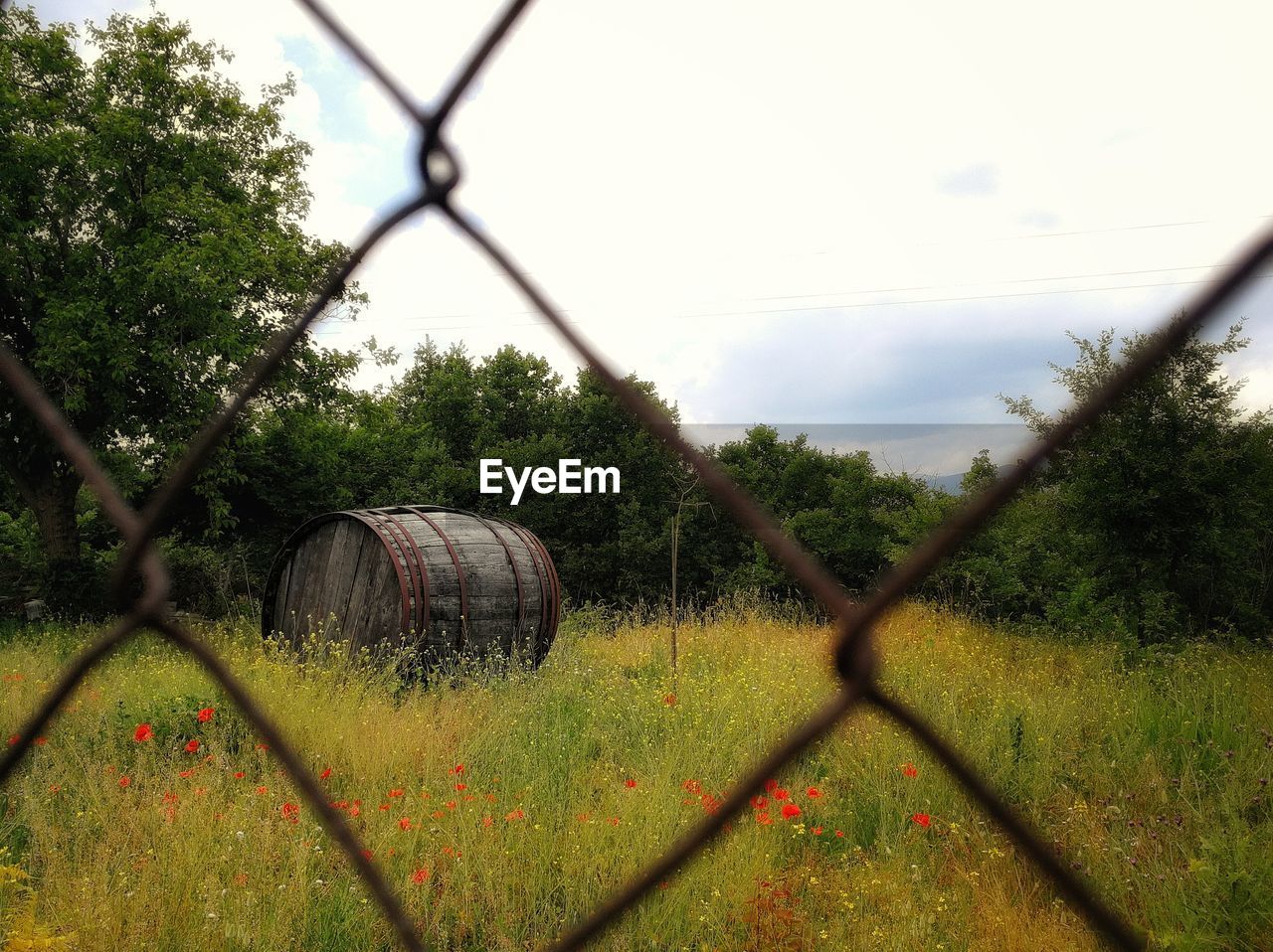 Scenic view of field against sky seen through chainlink fence