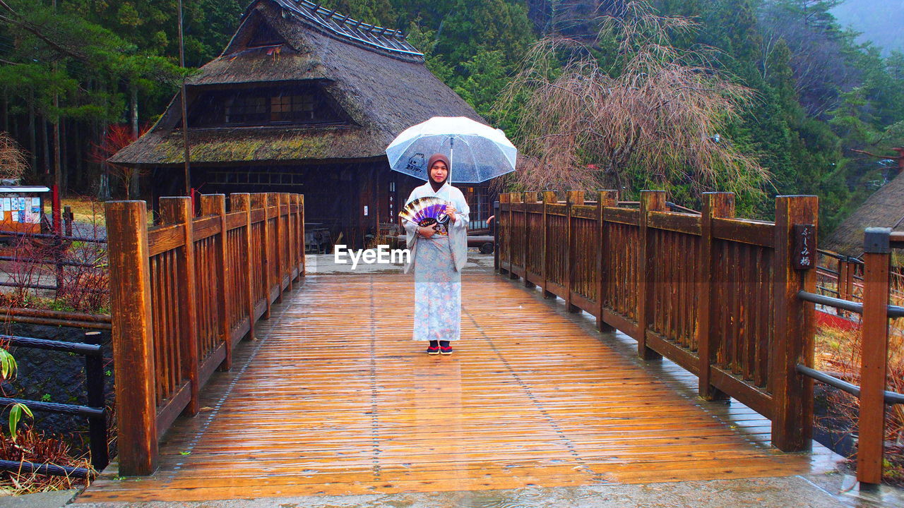 WOMAN STANDING ON FOOTBRIDGE DURING RAIN