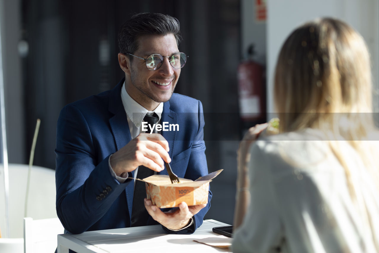 Business people having lunch while sitting in cafeteria at office