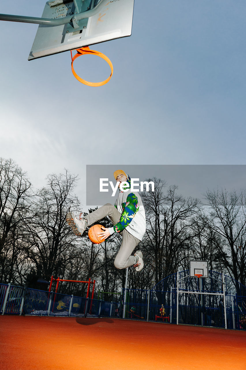 Man playing basketball against sky