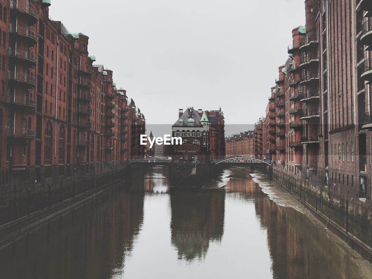 Canal amidst buildings against sky in city