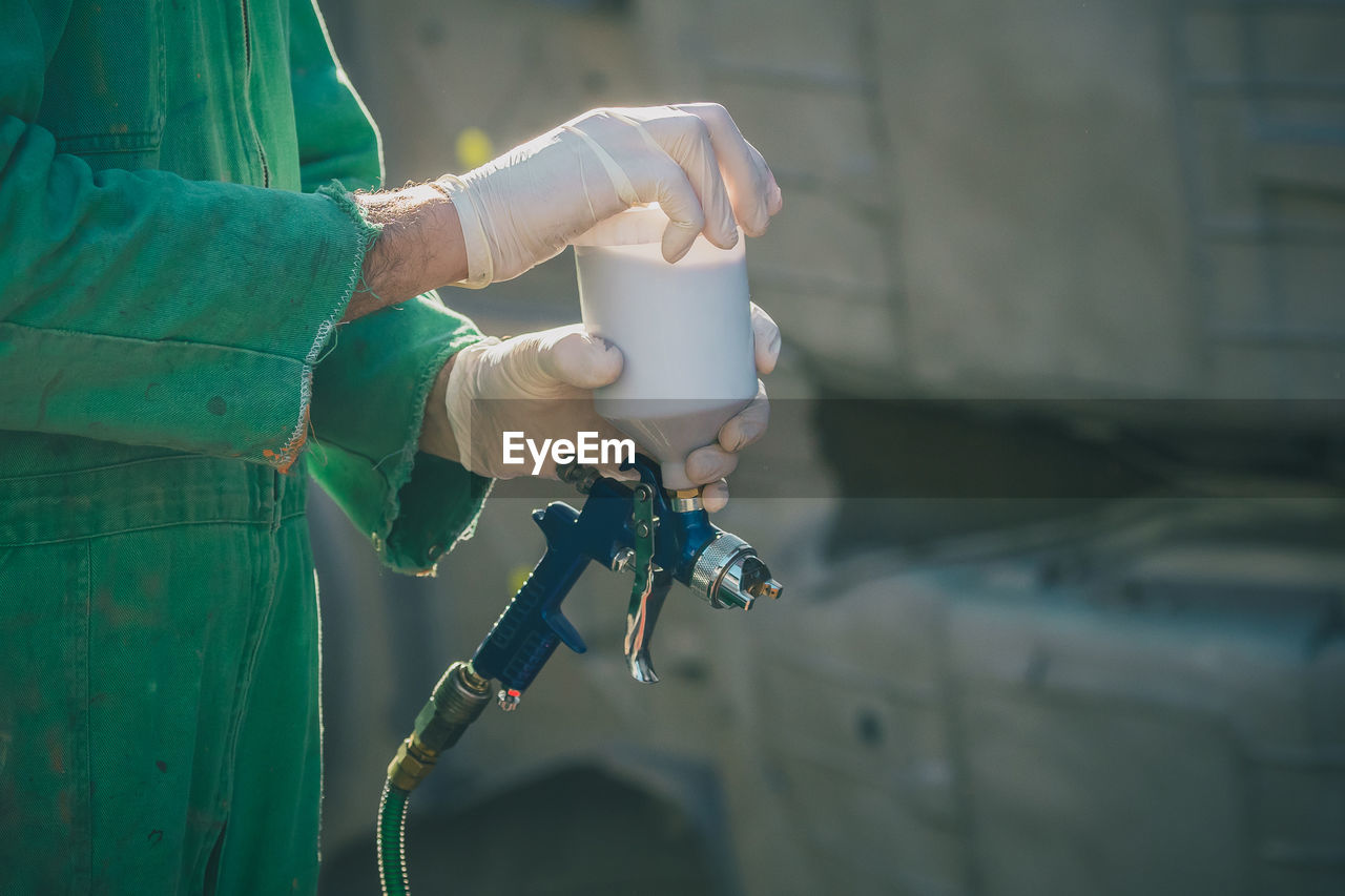 Midsection of woman holding paint spray gun