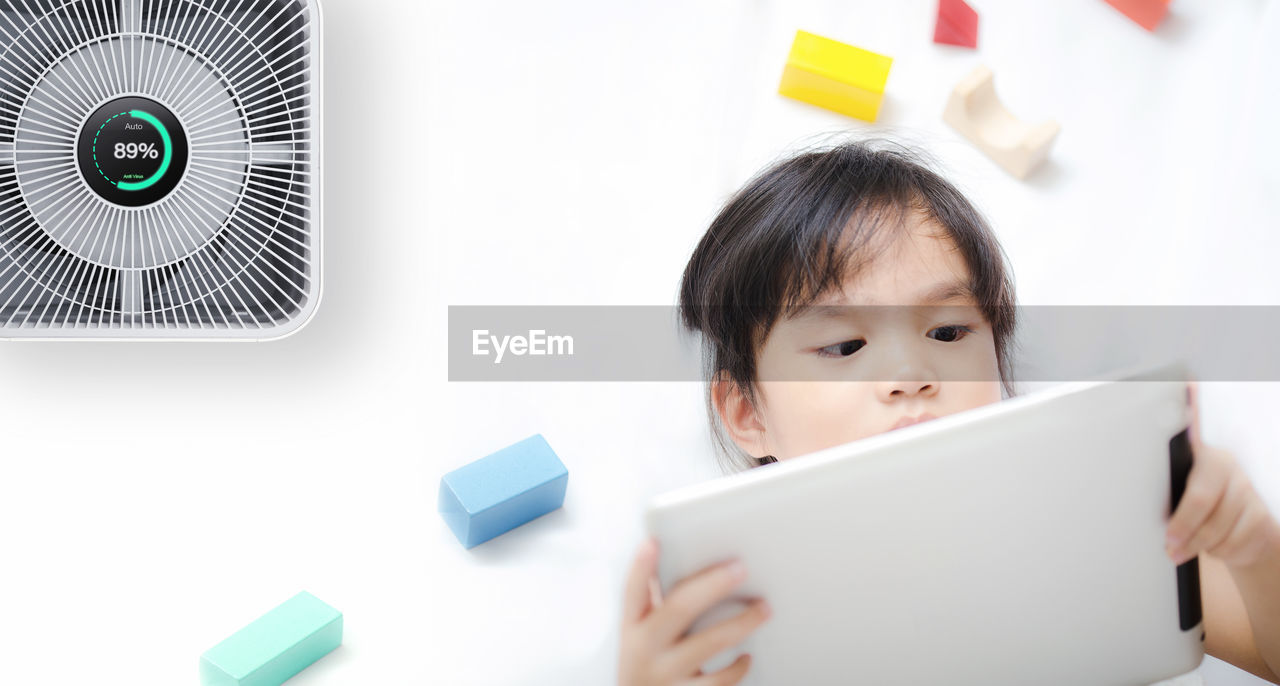 Little girl using tablet in room with modern air purifier