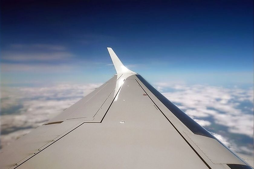 Cropped aircraft wing of airplane flying over clouds