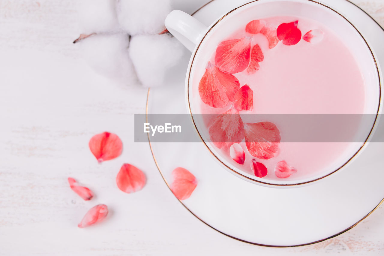 Trendy vegan tea on a white background. pink matcha with rose petals in a cup. relaxing drink recipe 
