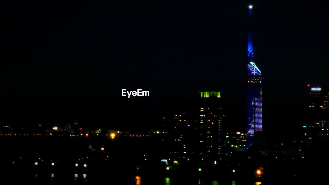 Illuminated city against clear sky at night