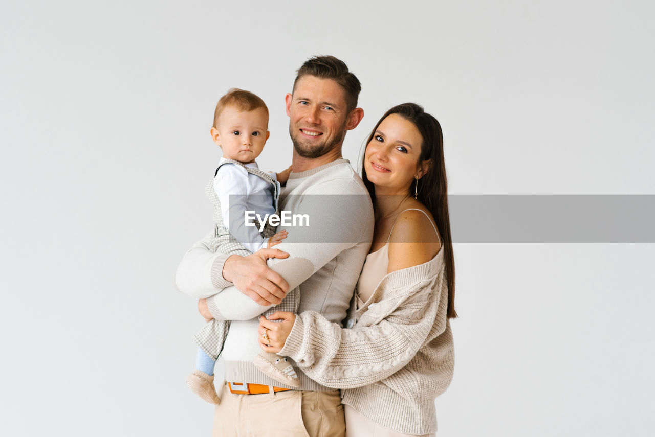 Portrait of a happy young family with a one-year-old son in their arms with copy space