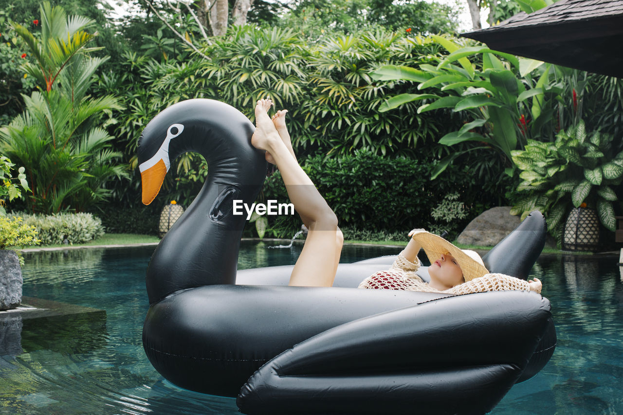 Young woman relaxing on swan shaped swimming float