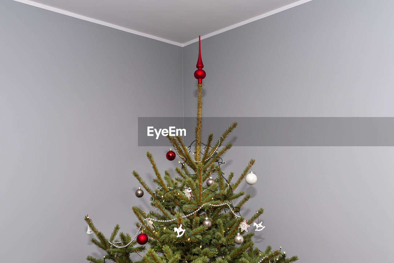 A spruce christmas tree decorated with baubles standing in the hall of a modern house.christmas tree