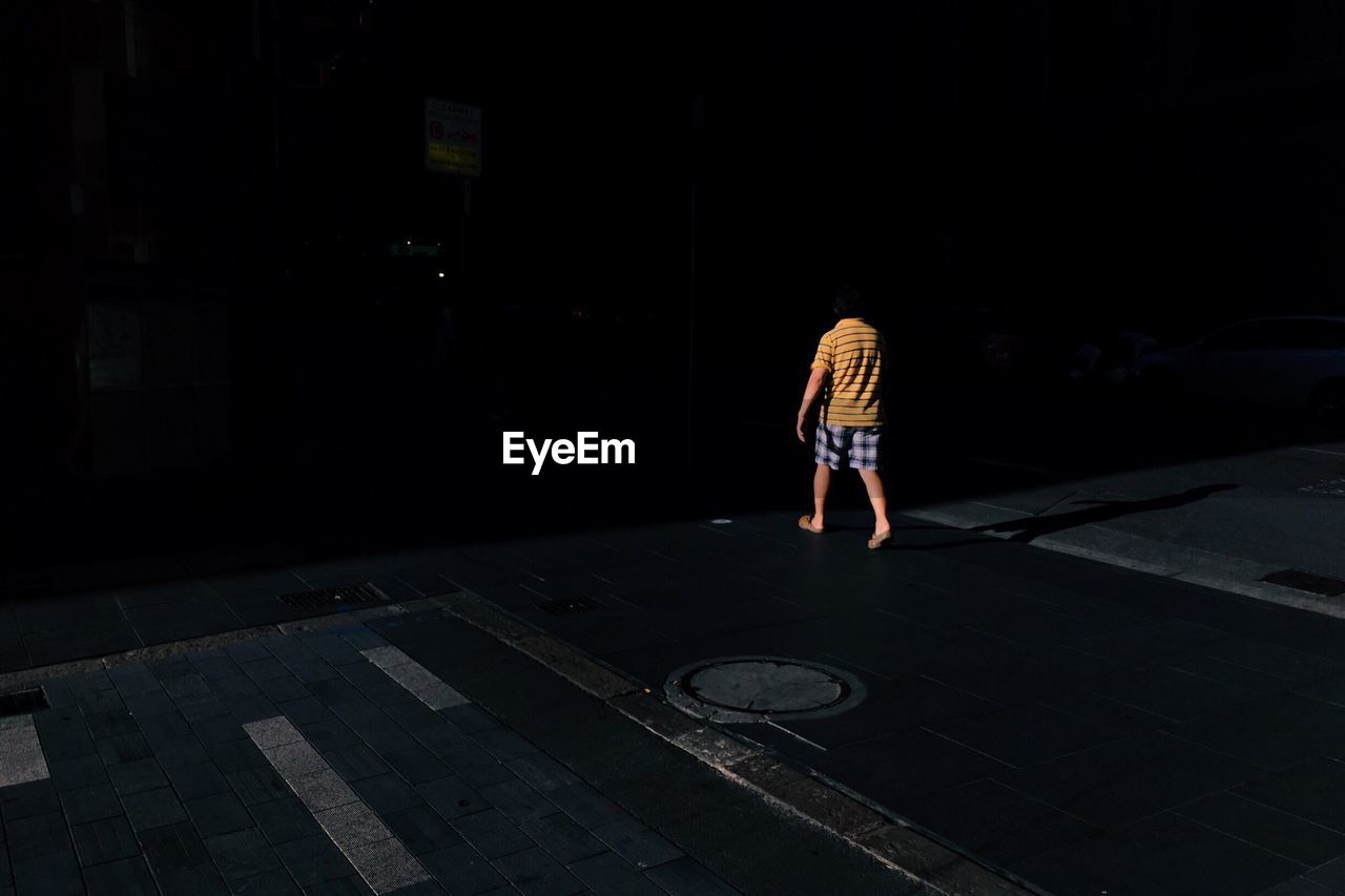 Rear view of man walking on street at night