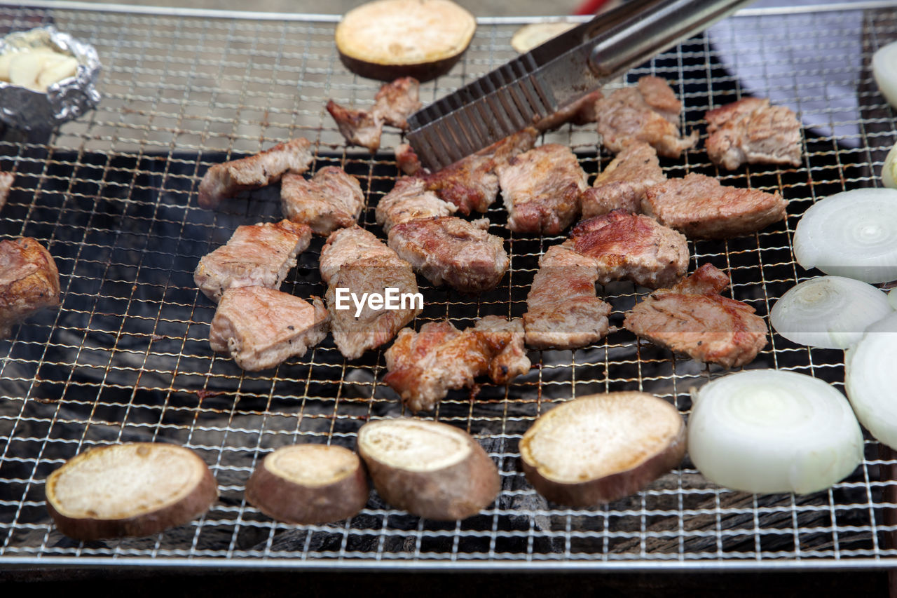 High angle view of meat and vegetable cooking on barbecue grill