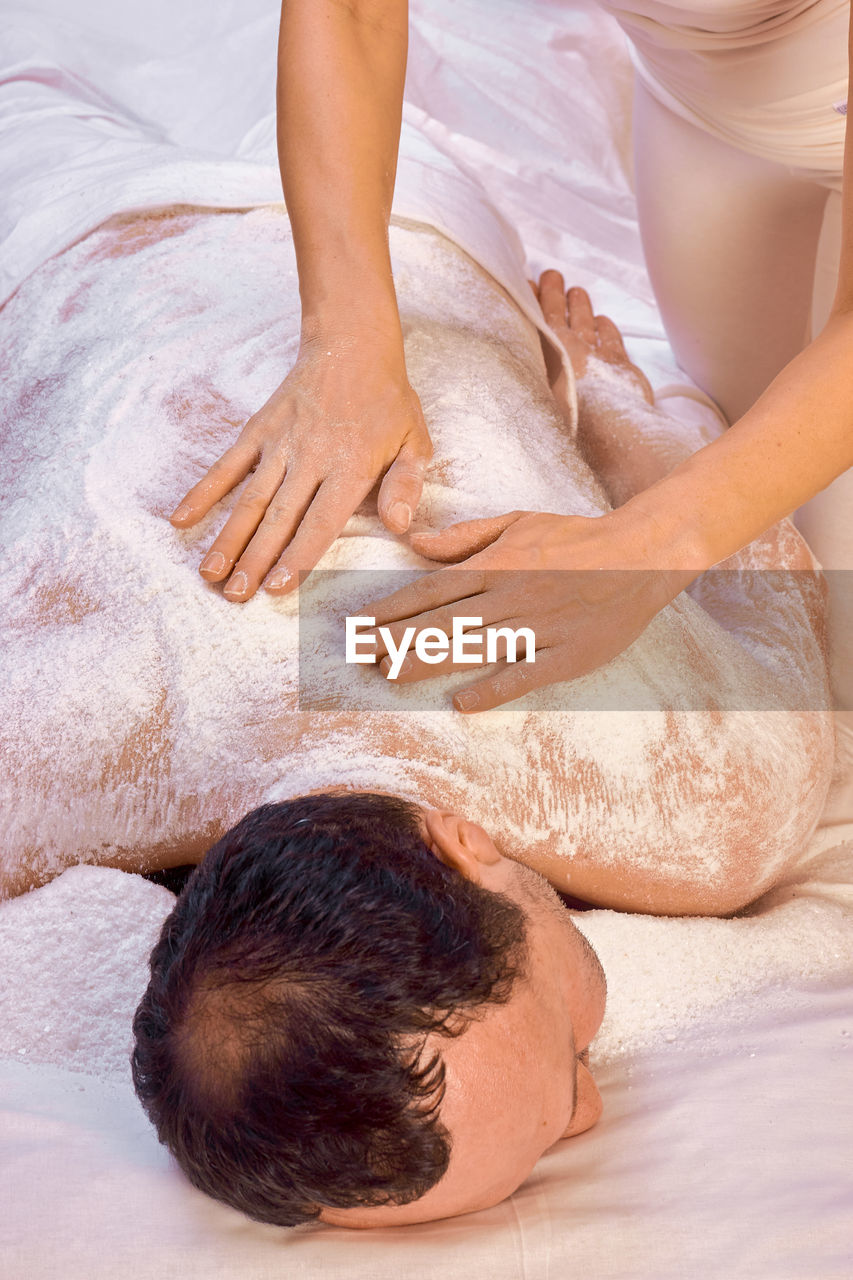 A woman healer performs a ritual with salt, rubs the back of a lying man with salt. 