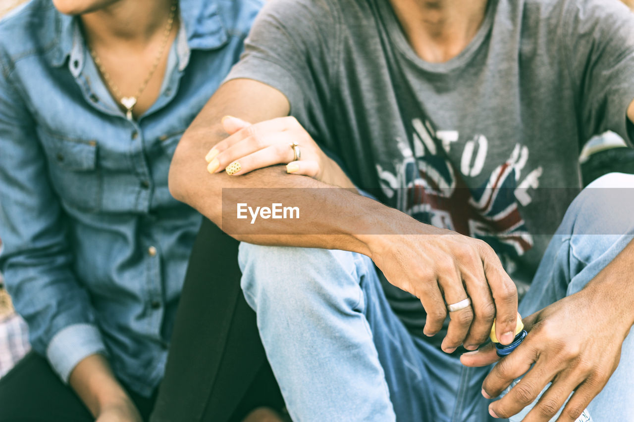 Midsection of couple sitting outdoors