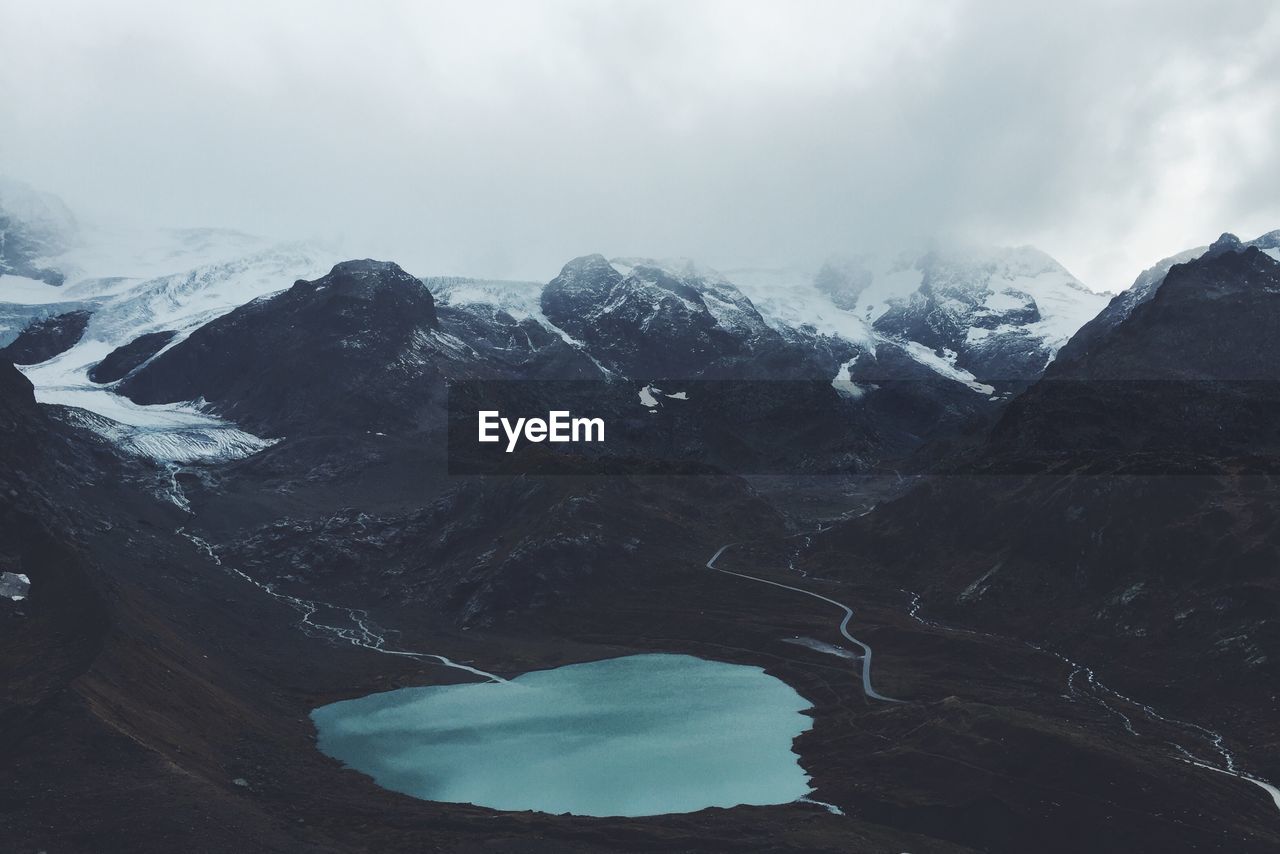 Scenic view of snowcapped mountains and lake against cloudy sky