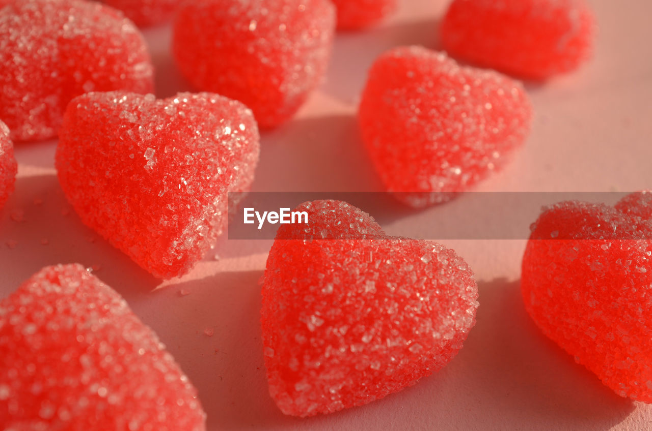 Red jelly hearts sugar coated candy on pink paper 