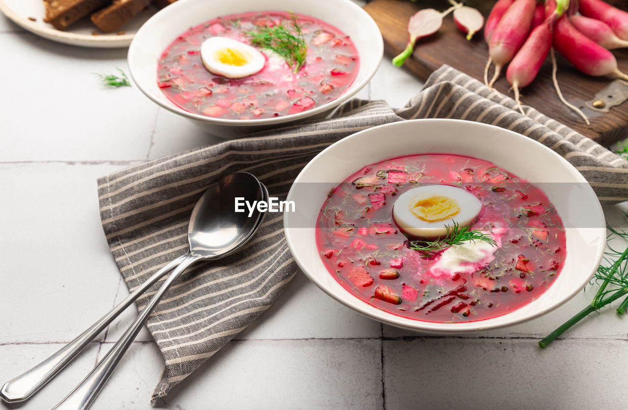 Summer cold beetroot soup with sour cream and egg on white tile background. russian cuisine. 