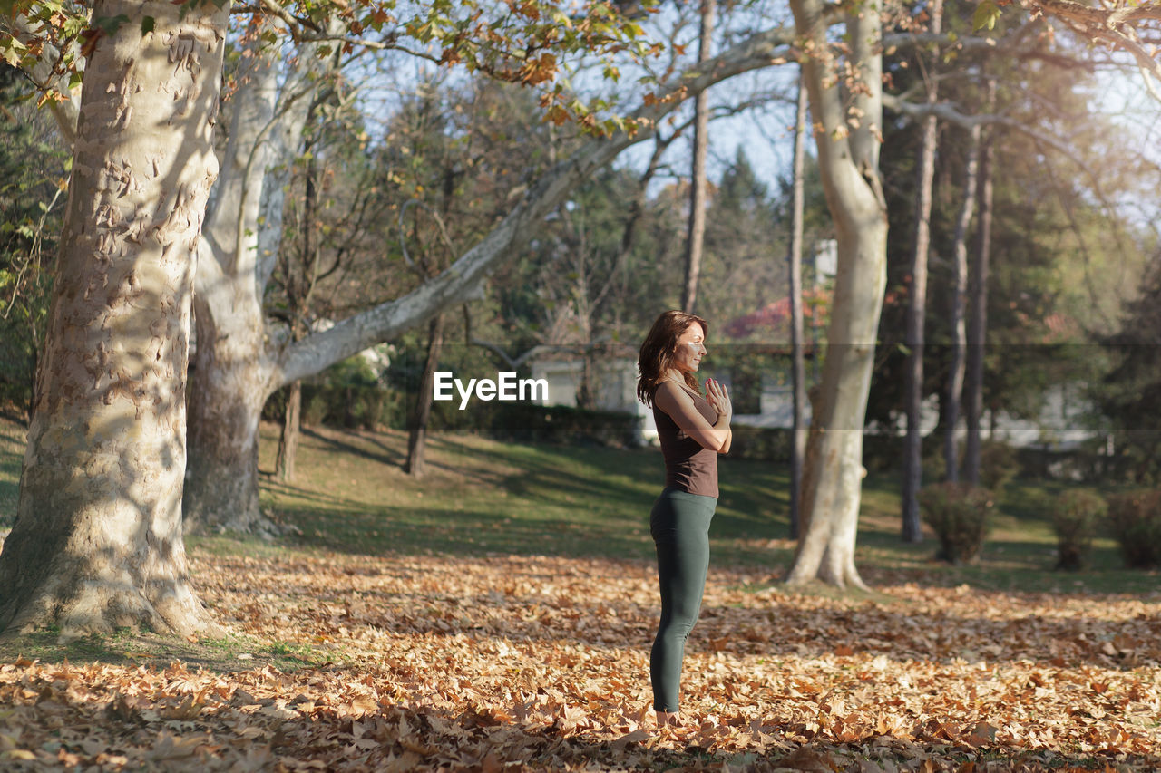 Full length of young woman standing in forest