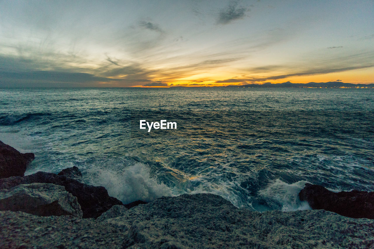 SCENIC VIEW OF BEACH AGAINST SKY AT SUNSET