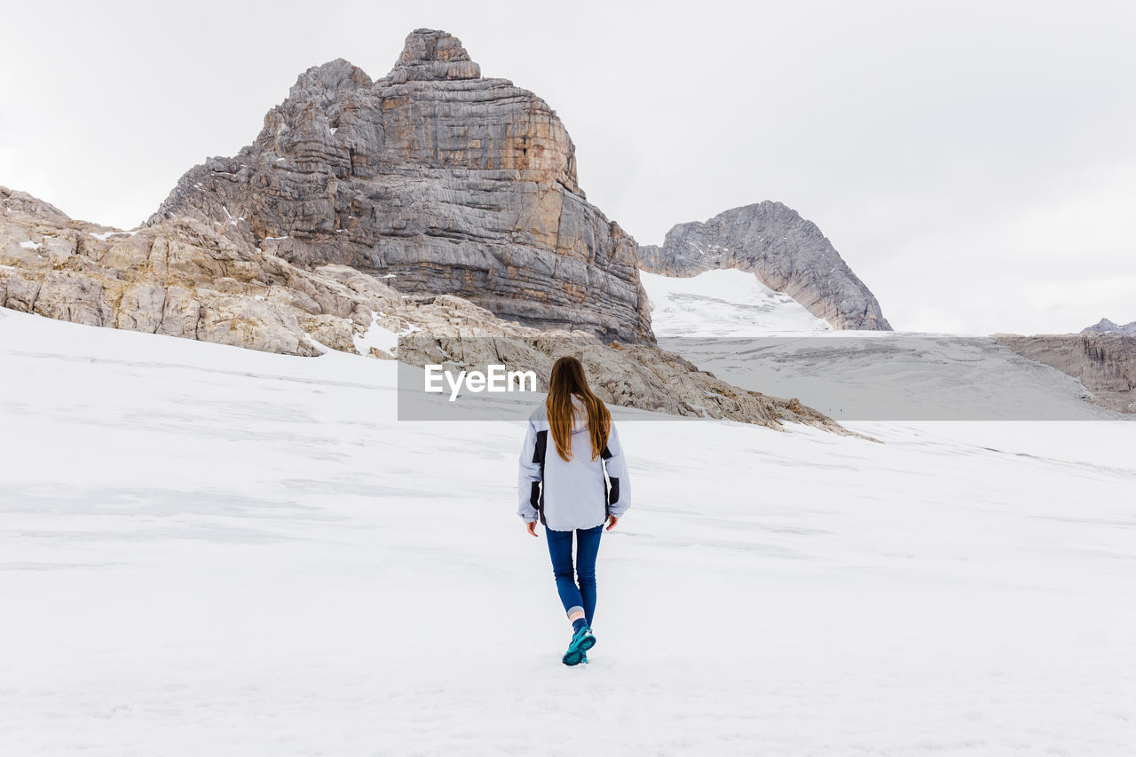 Young millennial girl enjoys the views of the alps standing on glacier