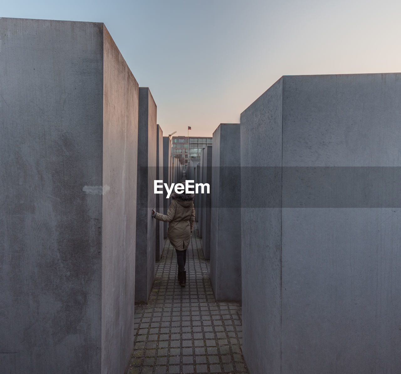 Rear view of man standing amidst holocaust memorial against sky