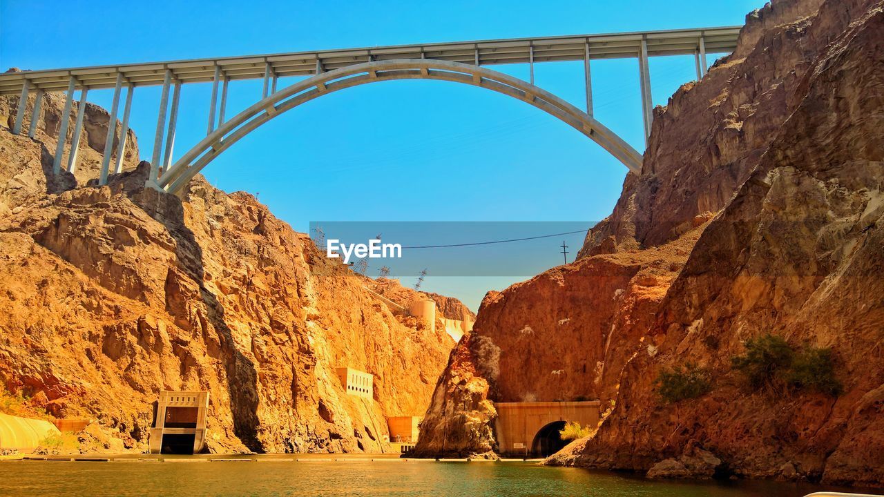 BRIDGE OVER RIVER BY ROCK FORMATION AGAINST SKY