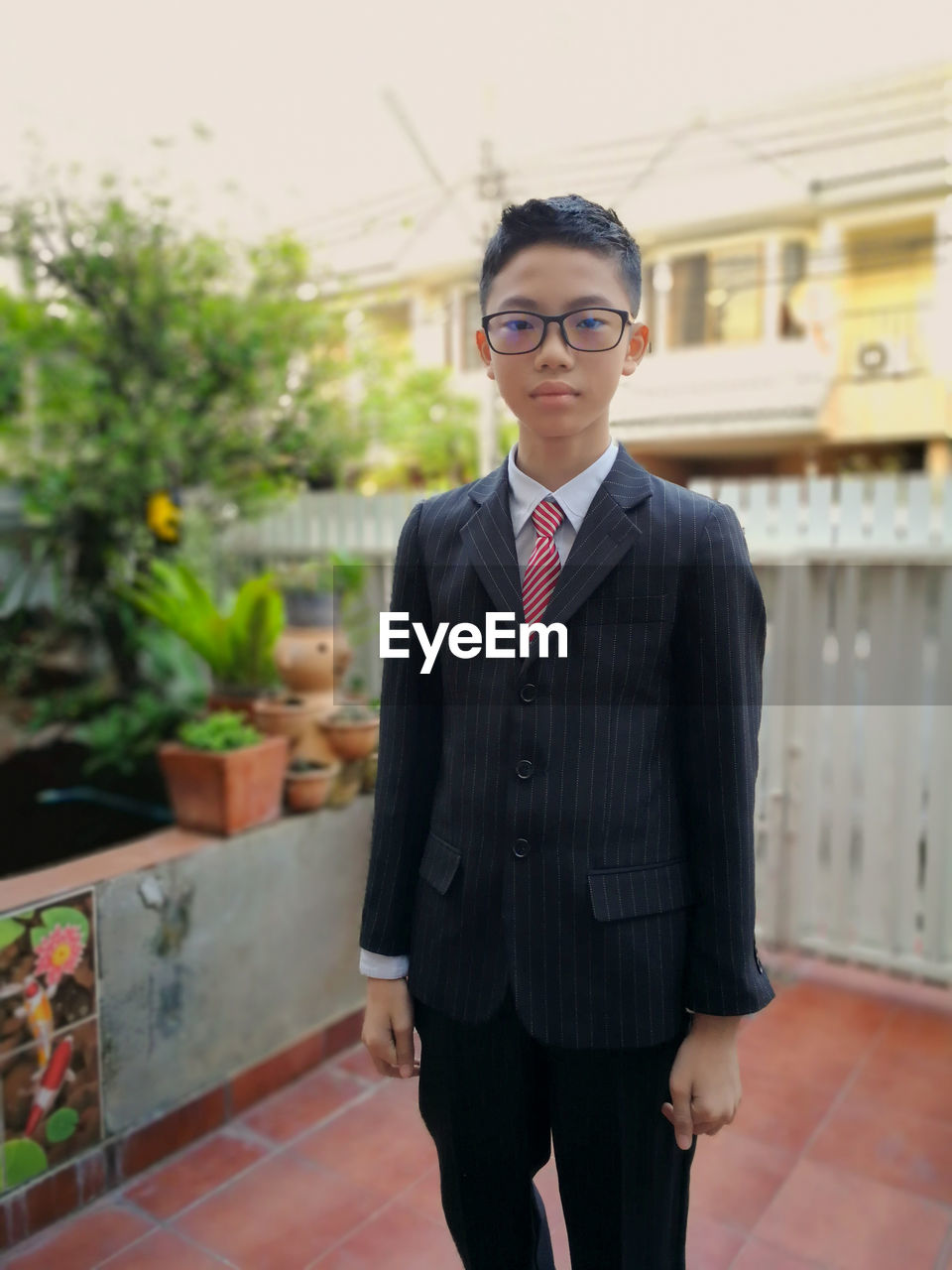 Portrait of boy wearing eyeglasses while standing against house