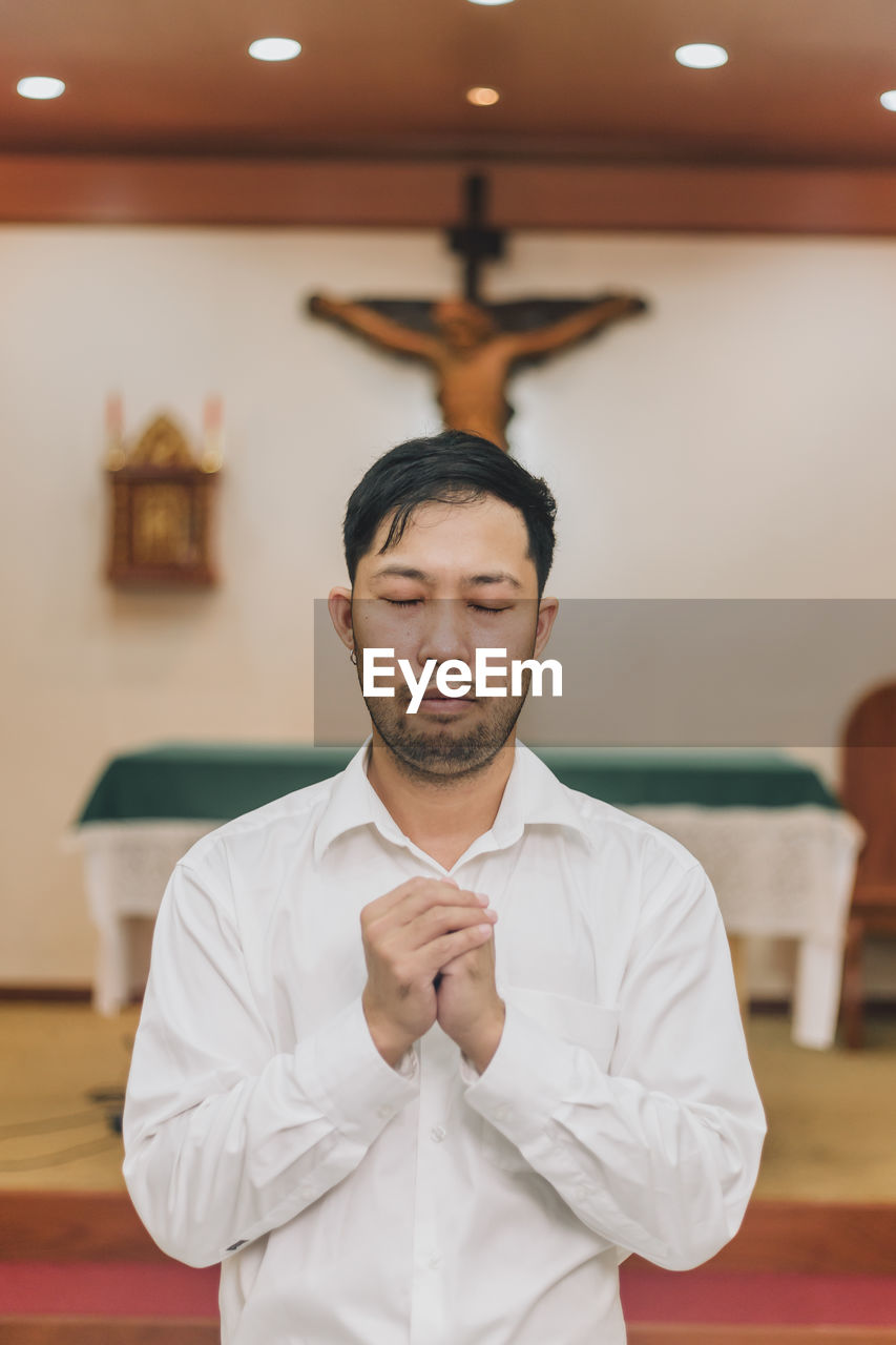 A christian man is sitting and praying with humble heart in the church.