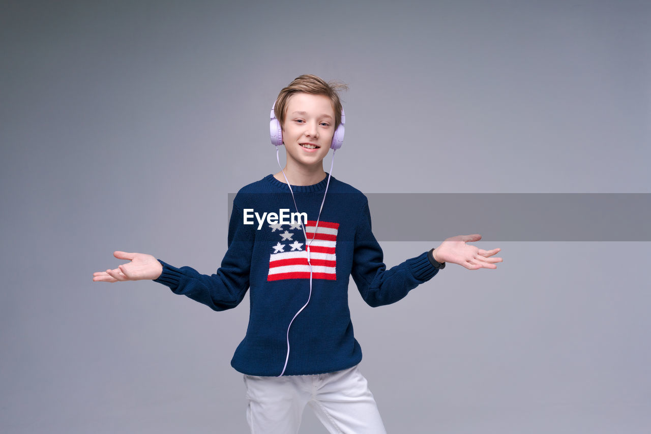 Joyful young man in blue sweater with flag america, stands listening to music