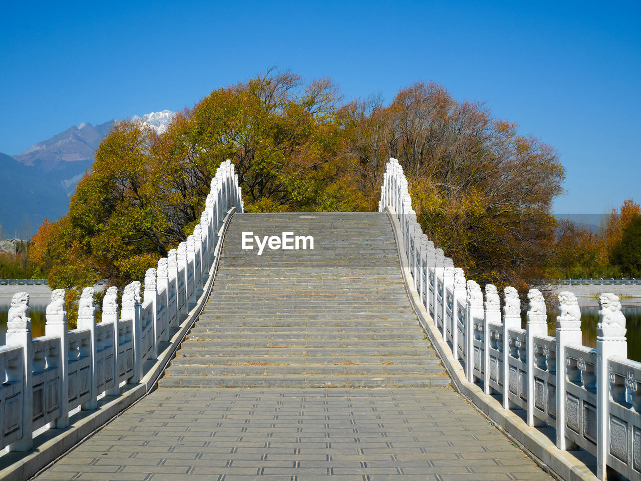 Stairway at qingxi reservoir with jade dragon snow mountain in the background in lijiang, china